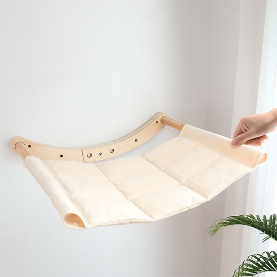 Main montrant l’installation simple du hamac mural avec support en bois ajustable.