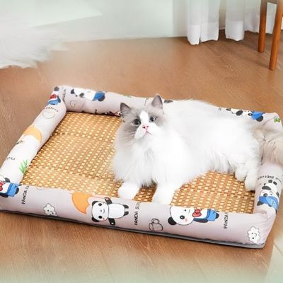 Chat blanc allongé sur lit pour chat beige à motifs panda et base en rotin naturel