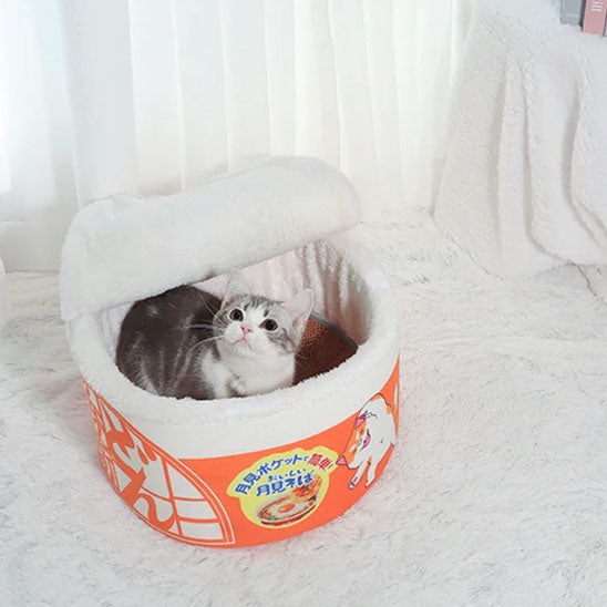Chat confortablement installé dans le panier pour chat Noodles bol de ramen avec couvercle semi-ouvert.