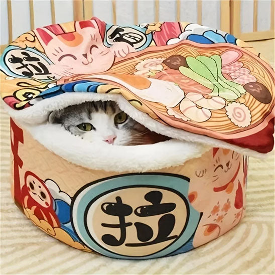 Chat gris assis dans le panier pour chat Noodles en bol de ramen avec couvercle relevé.