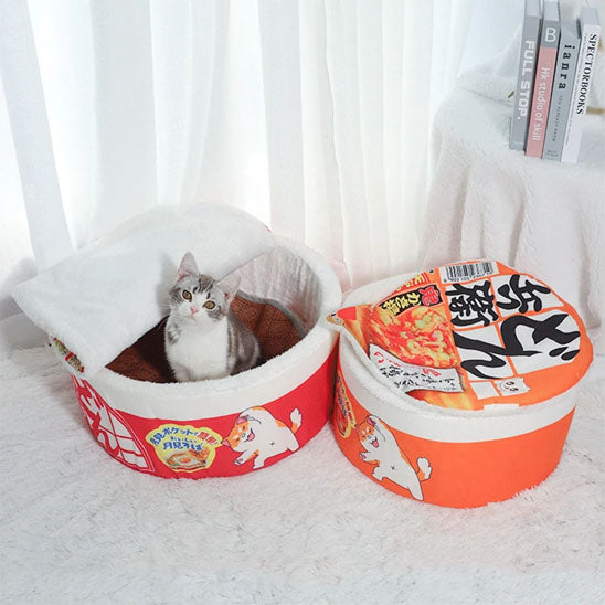 Chat gris assis dans le panier pour chat en bol de ramen avec couvercle relevé.