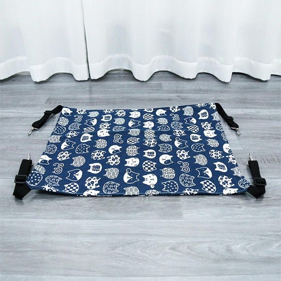 Vue à plat d’un hamac pour chat lavable et pliable en tissu bleu avec motifs de têtes de chat, sangles avec mousquetons visibles
