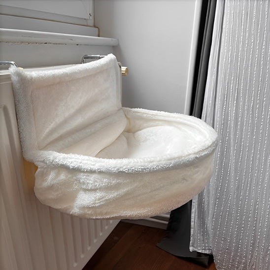 Hamac pour chat vide suspendu à un radiateur, avec coussin crème prêt pour la sieste