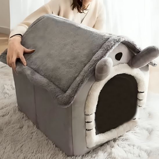 Personne tenant la niche pour chat FéliNiche sans fenêtre avec toit en peluche gris et oreilles souris.