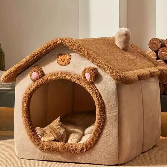 Chat endormi dans une niche beige CacheMiaou à toit brun, forme maison avec oreilles et ouverture ronde.