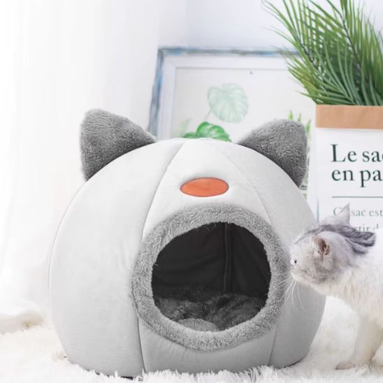 Chat observant une niche pour chat design en tissu gris clair avec intérieur moelleux