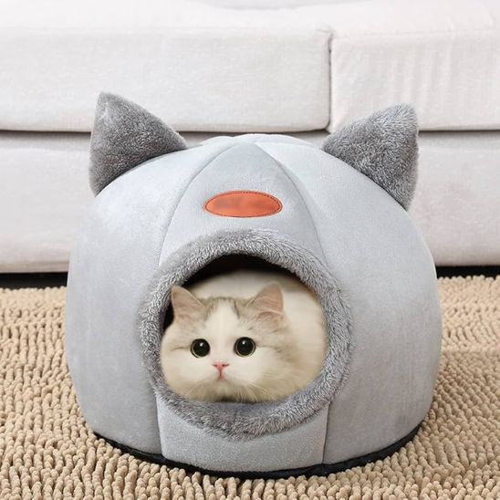 Chat blanc installé dans une niche pour chat douillette en tissu gris avec oreilles
