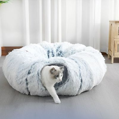 Chat sortant d’un tunnel pour chat avec ouverture latérale dans un coussin en fausse fourrure