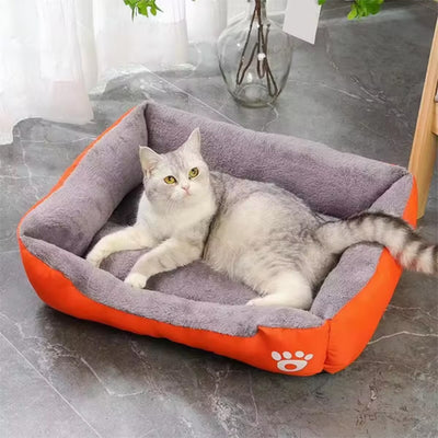 Chat allongé confortablement dans un lit pour chat orange ultra moelleux ChatLeureux sur sol en marbre.