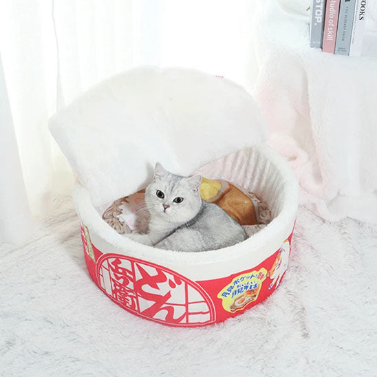 Chat blanc détendu dans le panier pour chat Noodles en forme de bol de ramen japonais.