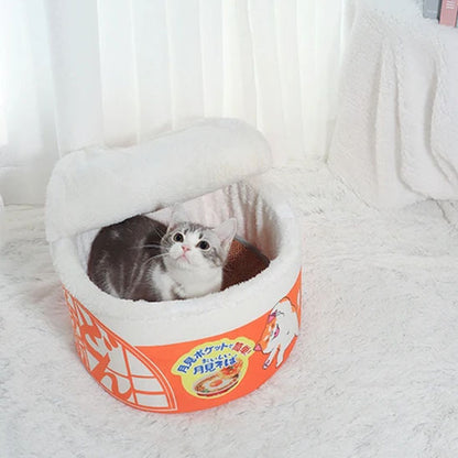 Chat confortablement installé dans le panier pour chat Noodles bol de ramen avec couvercle semi-ouvert.
