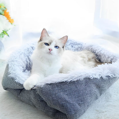 Coussin pour chat Chadoux gris moelleux, design apaisant pour intérieur moderne, avec un chat blanc aux yeux bleus relaxé.