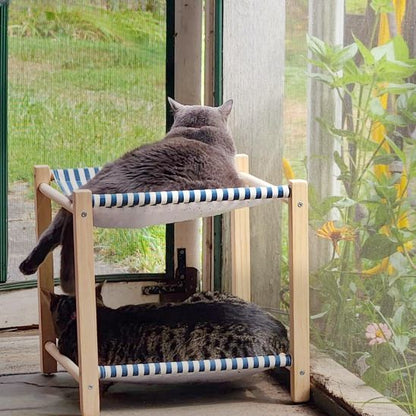 Deux chats sur un hamac pour chat design scandinave à deux étages, structure en bois clair et tissu lavable à rayures bleues