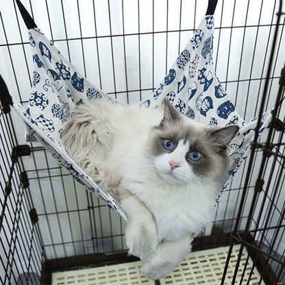 Chat ragdoll installé dans un hamac chat suspendu en coton bleu et blanc, motifs félins, accroché dans une cage intérieur