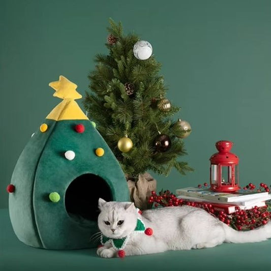 Niche pour chat en forme de sapin avec chat allongé à côté du sapin décoré