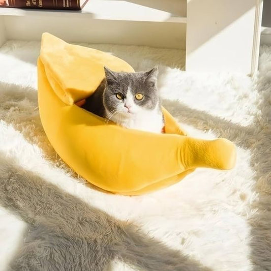Niche pour chat peluche jaune inspirée d’une banane, avec un chat paisiblement installé sur un tapis moelleux